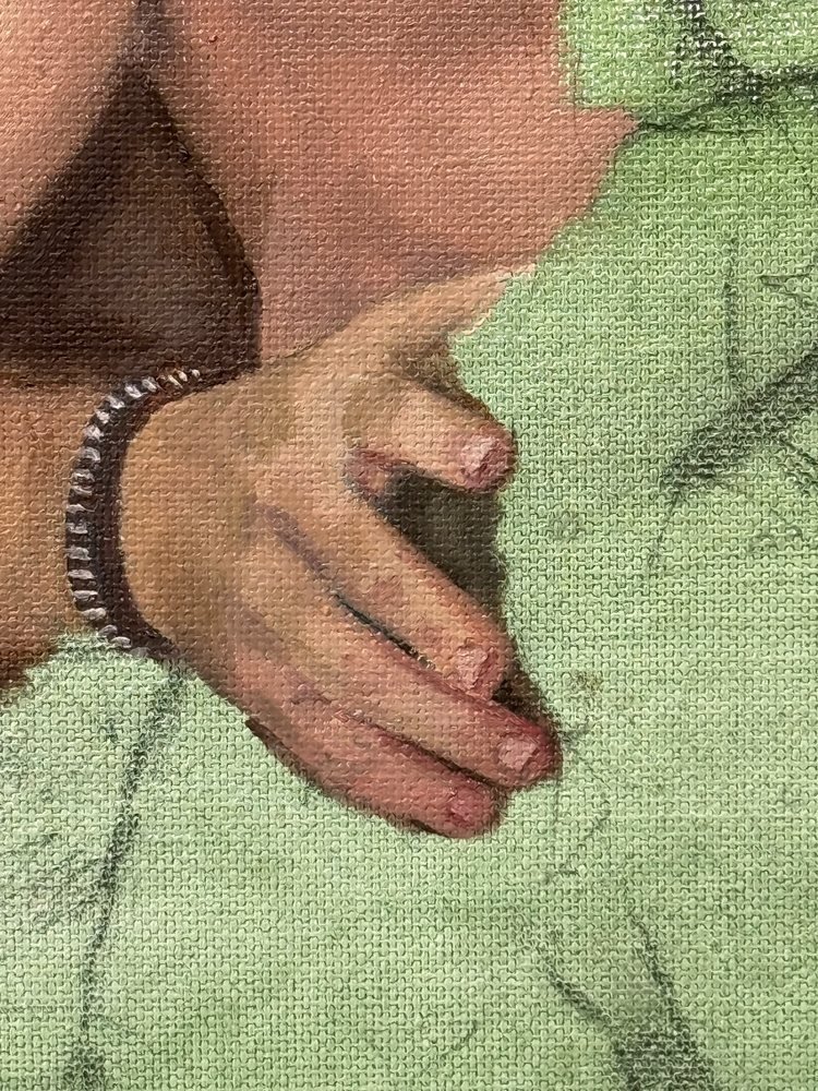 Close-up of a painted hand and bracelet against the green ground