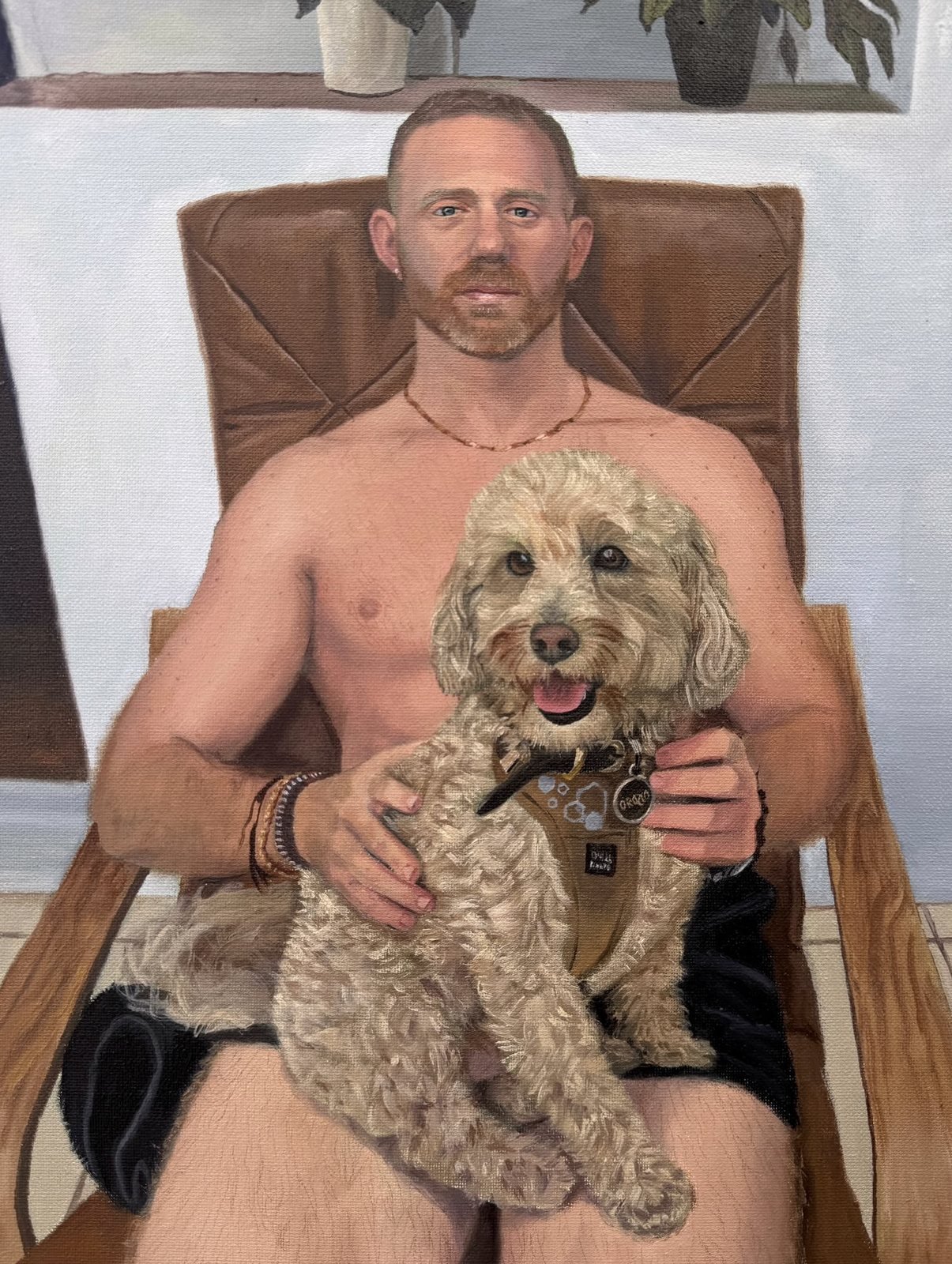 Finished oil portrait of Anthony in a leather chair holding Natty, a cream cockapoo