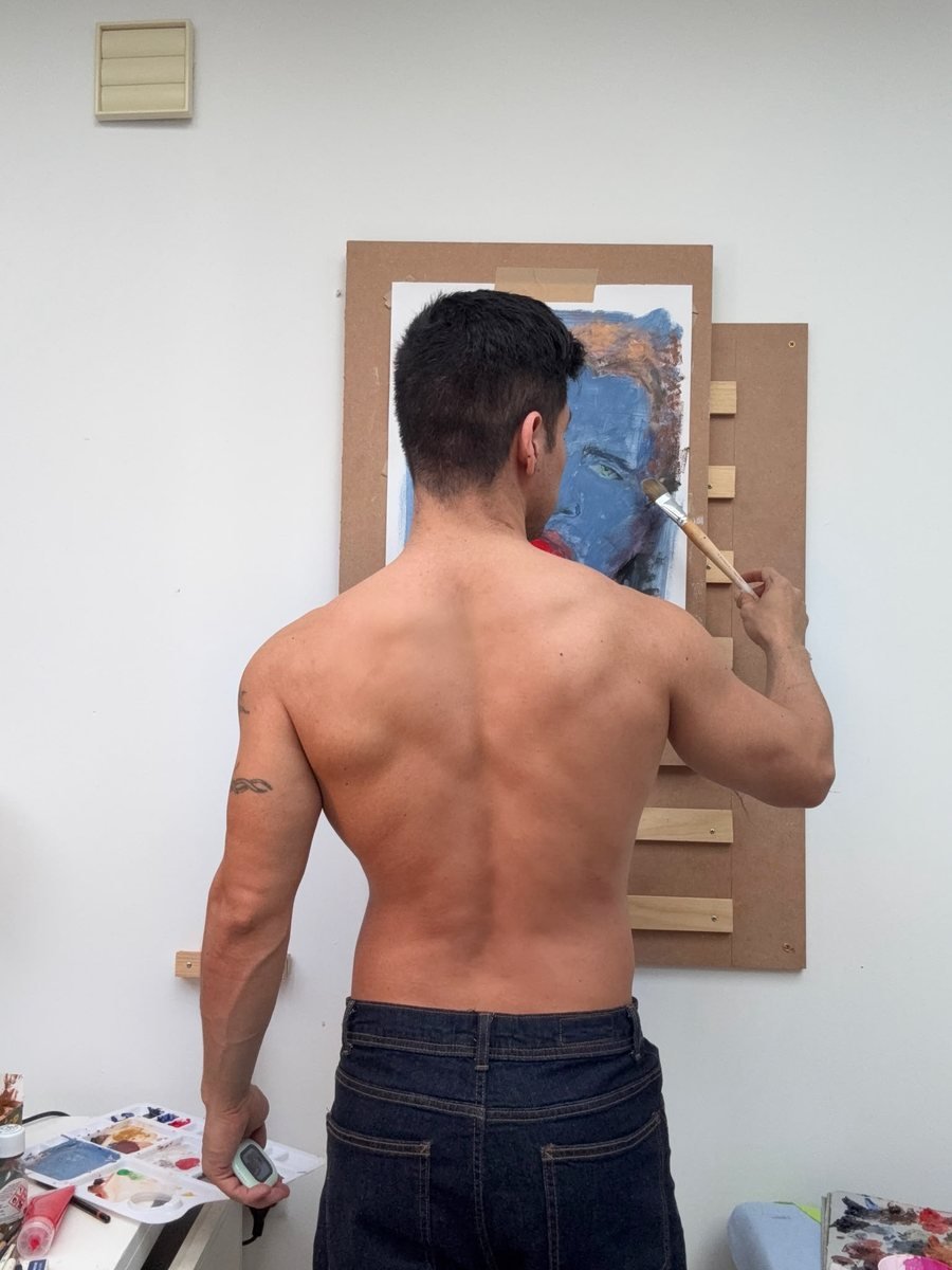 Dante, seen from behind, painting a blue portrait pinned to a board