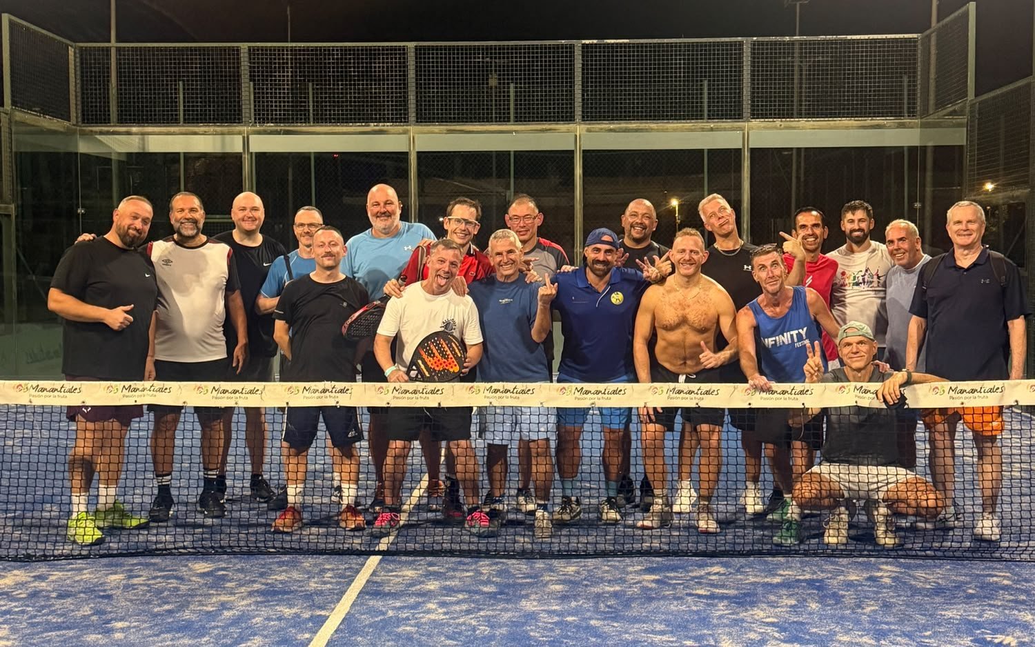 The All-Out Padel group with their hosts at the net on a floodlit court in Torremolinos